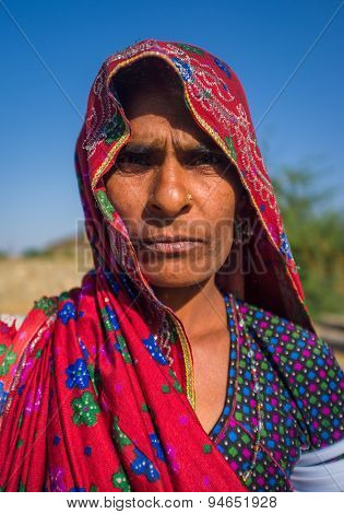 GODWAR REGION, INDIA - 14 FEBRUARY 2015: Rabari tribeswoman stands in field wearing saree and upper-arm bracelets. Rabari are an Indian community in the state of Gujarat.