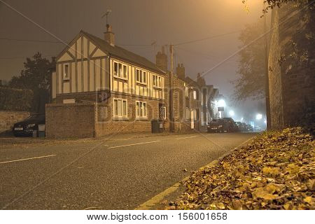 High Street Tarvin Cheshire UK - October 31 2016: Old arts and crafts house in a small village at misty Halloween night.