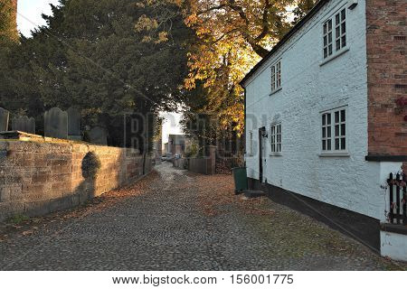 Tarvin Cheshire UK. Dawn light through road towards old farm buildings.