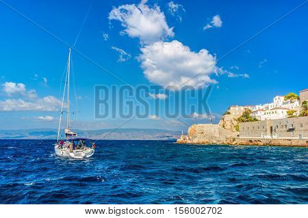 Hydra island on a summer day in Greece. Beautiful landscape with sea and island, and a boat sailing.