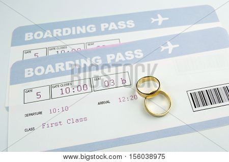 close up of a wedding rings on an airline boarding passes of a honeymoon