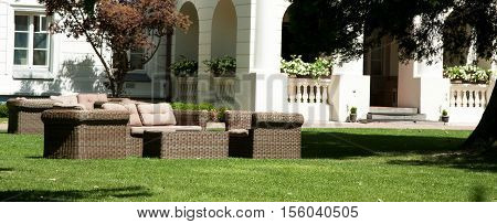 Garden furniture rattan brown standing on the green grass in front of the building