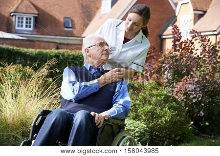 Female Carer Pushing Senior Man In Wheelchair