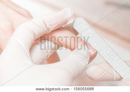 woman in a beauty salon receiving a manicure by a beautician with nail file. manicure closeup