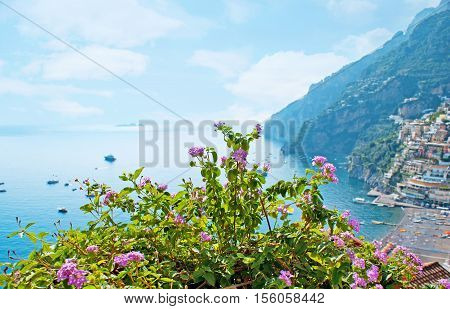 The coast of Positano with nice beach boats and yachts colorful cottages through the bright flowers on the Italy.