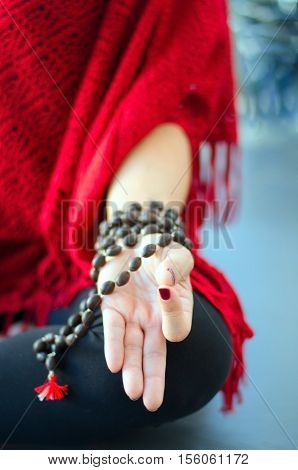 Woman hand in yoga mudra with mala beads. Colorful blurred background. Concept for concentration or meditation.