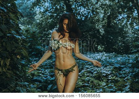 portrait of slim sexy girl in underwear leaf looking at the camera outdoors in the forest
