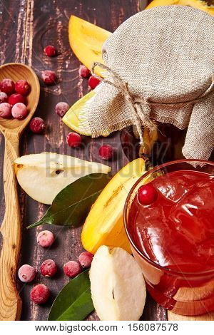 Berry and fruit jam with ingredients on a dark rustic background.