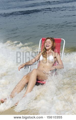 snapshot: donna ridendo sulla spiaggia sorpresa dalle onde dell'oceano