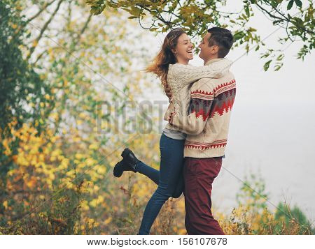 Young attractive couple in knitted sweaters having fun at sea shore