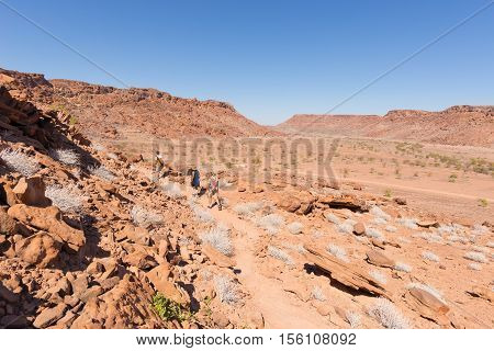 Twyfelfontein, Namibia - August 27, 2016: Group Of Tourists Walking In The Desert At Twyfelfontein,