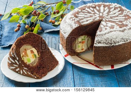Delicious homemade chocolate cake with whole apples curd and candied fruit on a blue wooden table