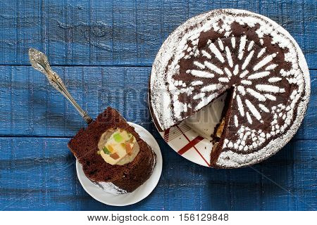 Baking in multicooker. Delicious homemade chocolate cake with whole apples curd and candied fruit on a blue wooden table. Top view