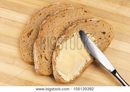 Close up a knife spreading butter on bread