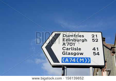 Scottish road sign showing direction to Dumfries, Edinburgh, Carlisle, Glasgow and Moffat Mill, in the town of Moffat, Scotland, UK