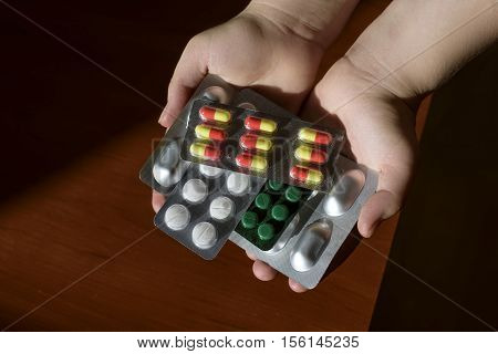 woman's hands holding a handful of pills medicine