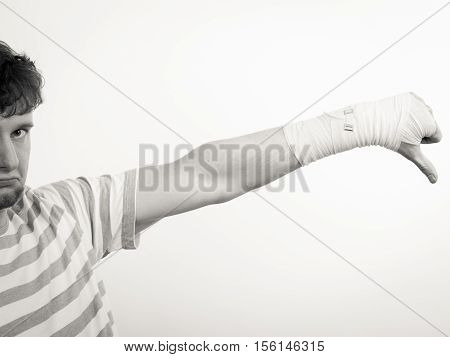 Bad news and information. Medicine aspects. Sad unhappy male with bandaged hand showing thumb down sign symbol.