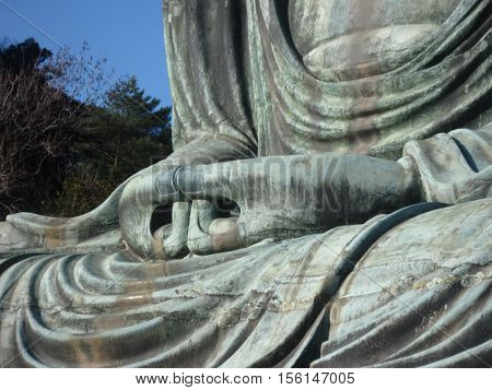 Hands together of a monumental outdoor bronze statue of a Buddha in  Kamakura, Kanagawa Prefecture, Japan.