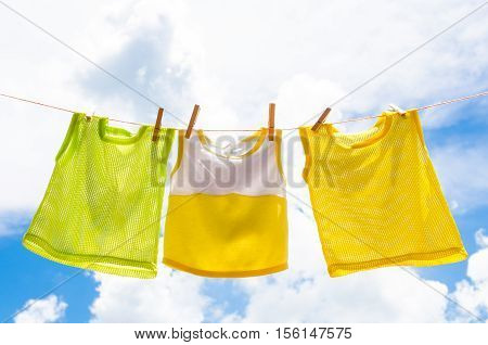 Baby clothes laundry hanging on the clotheline for sun dry after wash over blue sky in sunny day