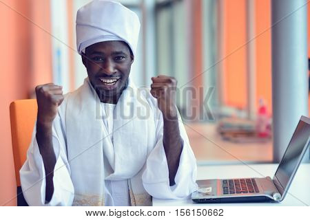 Sudanese business man in traditional outfit using mobile phone in office.