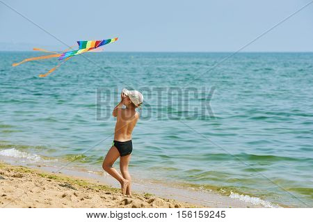 Little boy resting and playing on the beach with a kite