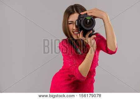 Beauriful brunette woman in red dress makes a photo in studio