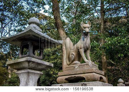 Statue of Kitsune fox holding a key in its mouth at the main gate to the Fushimi Inari-taisha shrine near Kyoto. Japan.