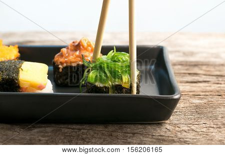 Close Up Of Chopsticks Taking Portion Of Sushi Roll On The Table Restaurant / Eating Sushi Roll Usin
