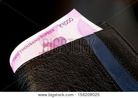 New Indian rupee 2000 note placed in a black leather wallet and isolated on black. The new currency has been introduced to curb black money