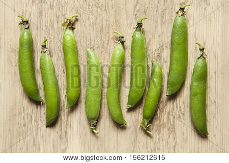 Green pea pods on a wooden background.