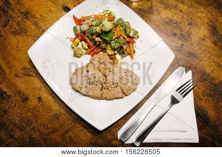 Fillet of tuna with vegetables. Wooden table.