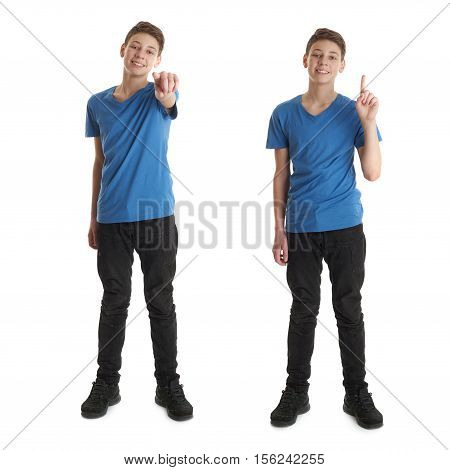 Cute teenager boy in blue T-shirt standing and poinitng forward over white isolated background full body