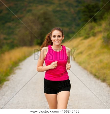 runner - woman runns on a forest road - outdoor workout