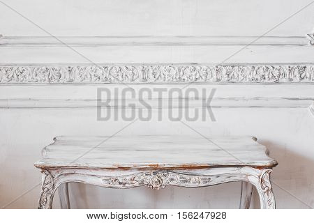 Living room with antique stylish light Coloured table on luxury white wall design bas-relief stucco mouldings roccoco elements.
