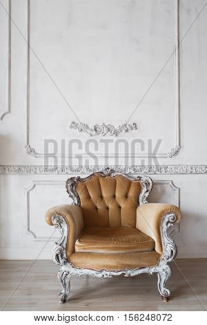 Living room with antique stylish beige armchair on luxury white wall design bas-relief stucco mouldings roccoco elements.