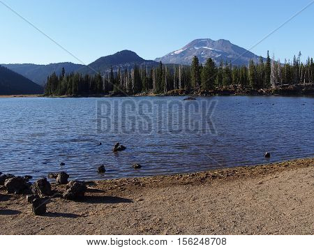 Sparks Lake and its shores with Sout Sister of Oregon's Cascade Mountains in the background on a sunny day.