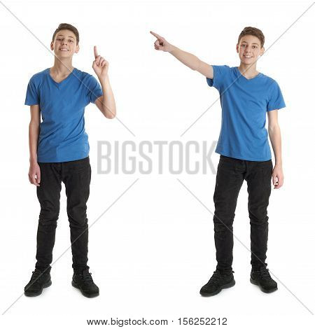 Cute teenager boy in blue T-shirt standing and poinitng up over white isolated background full body