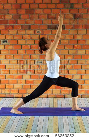 Woman practicing yoga against a brick wall