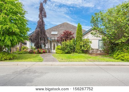 Custom built house on a sunny day with front yard and nicely trimmed lawn.