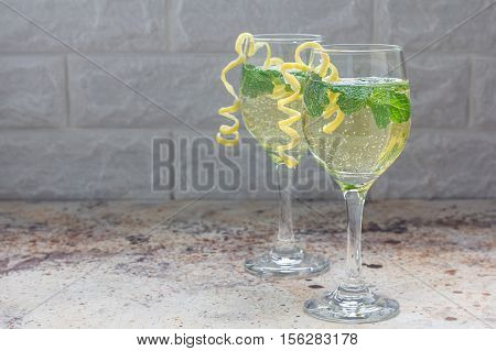 Spritzer cocktail with white wine mint and ice decorated with spiral lemon zest horizontal copy space