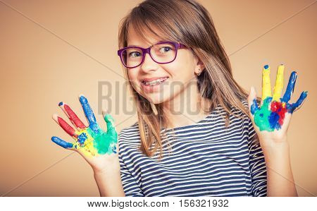 Portrait of a little pre-teen student girl showing painted hands. Toned Photo.