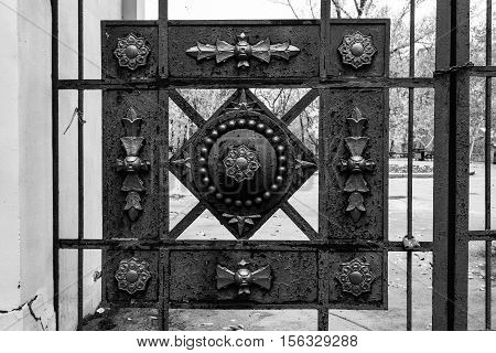Wrought iron gates of the park. Decorative elements. Black and white photo.