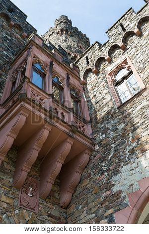 Ancient stone wall with windows and carved balcony against the blue sky bottom view. Reichenstein Castle Rhine Valley Germany - UNESCO World Heritage