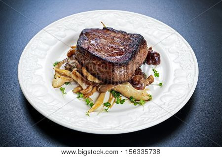 Tasty Beef Mignon steak with mushrooms and herbs on plate