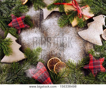 Christmas border composed of handmade christmas toys, fir branches, sliced oranges over a wooden background with space for text, overhead view. Christmas or new year card. Vintage. Rustic .