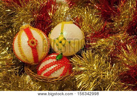 Christmas balls decorated with yellow and red beads in yellow shiny tinsel