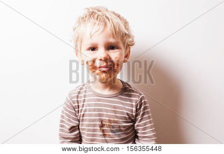 Portrait of fair-haired boy with chocolate on his face isolated on white