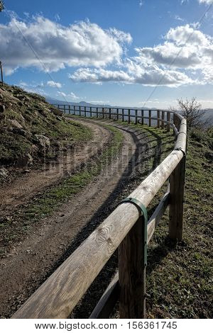 curve dirt road and fence under cloudy sky of Nebrodi Park, Sicily