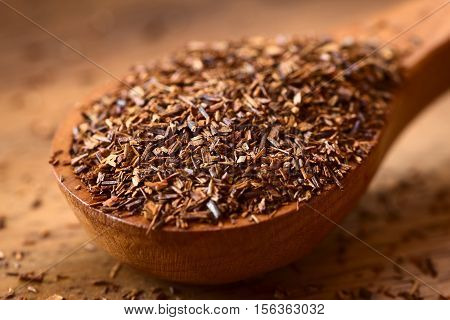 Rooibos herbal tea on wooden spoon photographed on wood with natural light (Selective Focus Focus one third into the leaves)