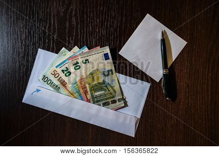 White envelope with Euro bills over wooden background